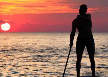Man on paddleboard in the ocean during sunset