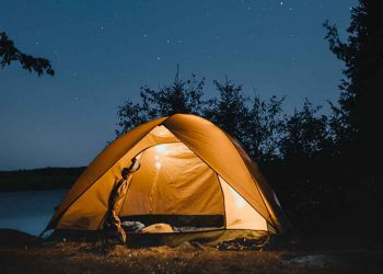 Glowing camping tent under starry night sky