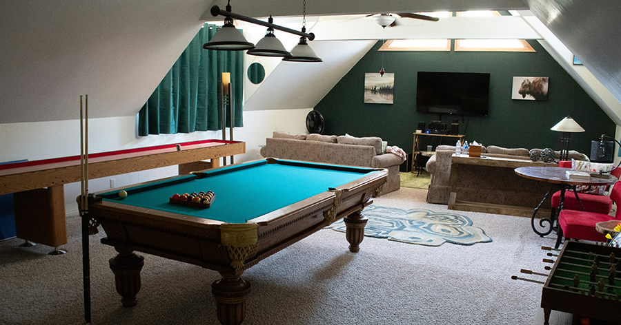 A room with a pool table and couch and television
