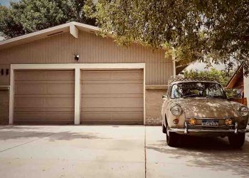 tan garage and car parked next to tree