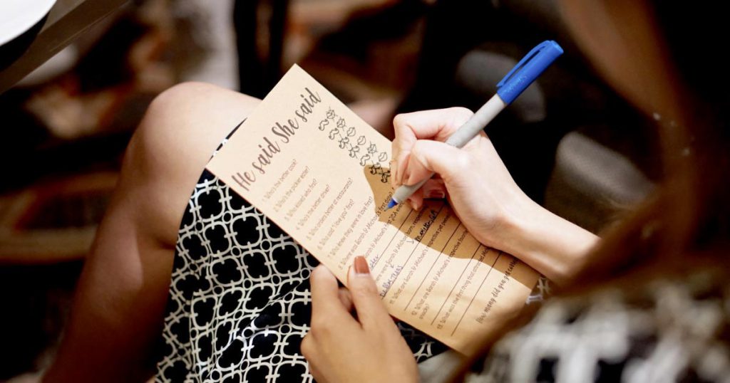 View over a woman’s shoulder as she fills out her answers for a “he said/she said” game at a friend’s small bridal shower.