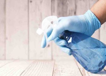 Person with gloves and spray bottle cleaning.