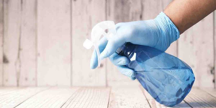 Person with gloves and spray bottle cleaning.