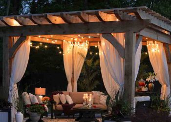 Pergola with drapes, lights, and furniture
