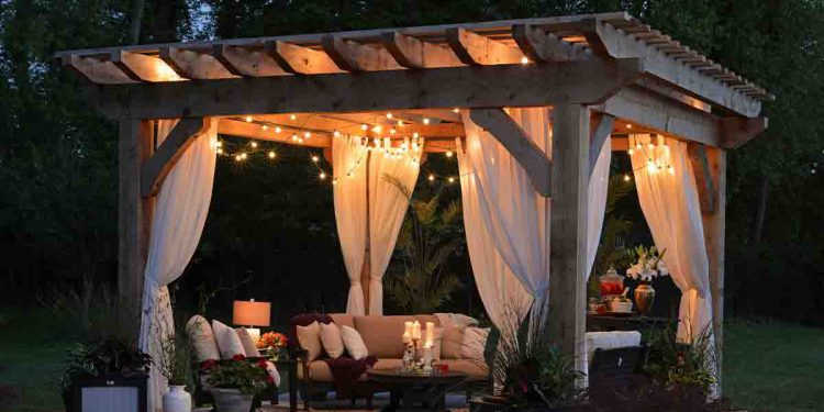 Pergola with drapes, lights, and furniture