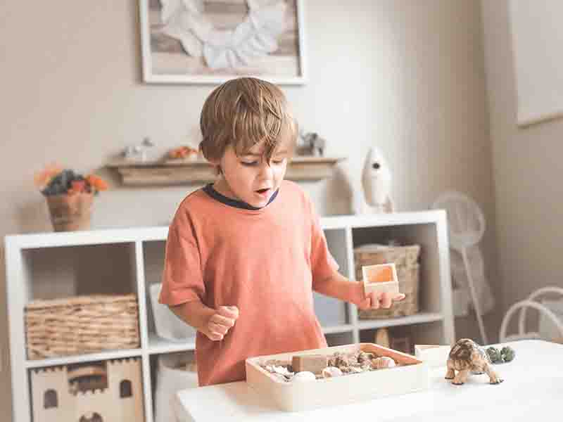 Boy with orange shirt playing at a table
