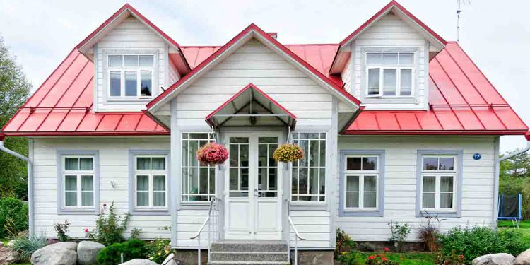 White and red cottage with flowers hanging on porch