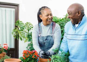 Couple potting plants and smiling