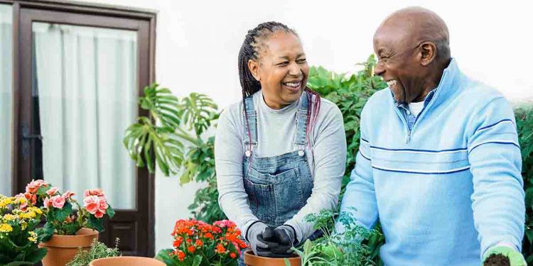 Couple potting plants and smiling