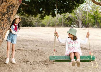 two girls playing on a swing