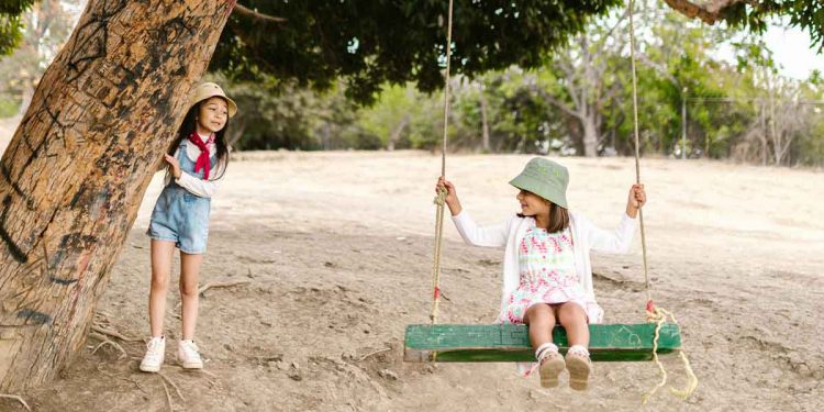 two girls playing on a swing