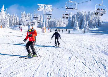 Two people skiing down a snowy mountain
