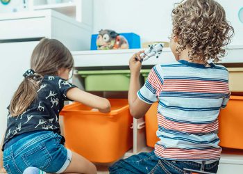 children playing next to toy storage bins