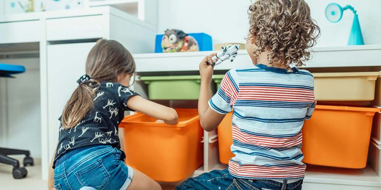 children playing next to toy storage bins