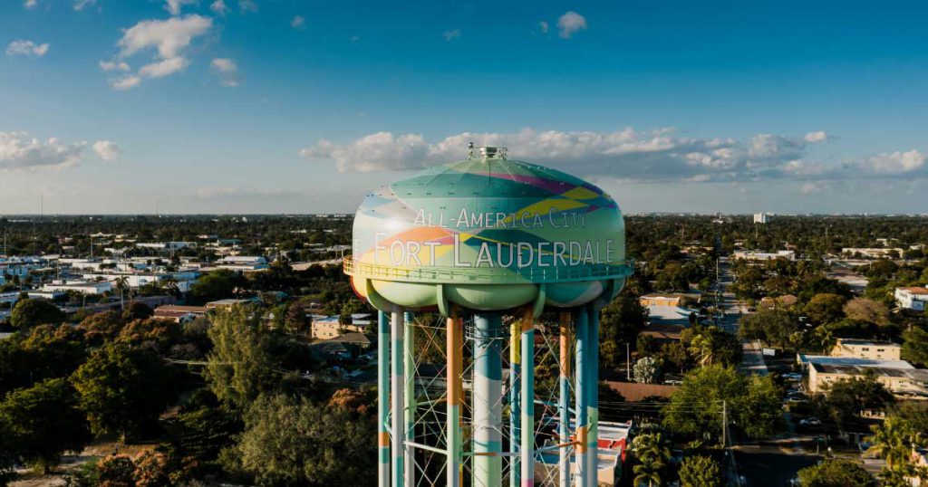 A colorful water tower featuring the words ‘All-America City Fort Lauderdale’ painted on its side, surrounded by the best neighborhoods in Fort Lauderdale.