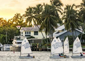 A small group of locals living in Fort Lauderdale sails dinghies past waterfront homes as the sun begins to set.