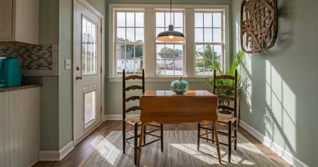 A breakfast nook with walls painted in jade and natural wood furniture accents.