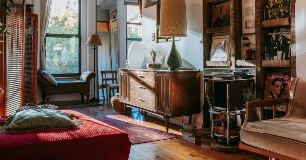 A sunlit living room with vintage furniture, records, and wood floors in a colorful home.