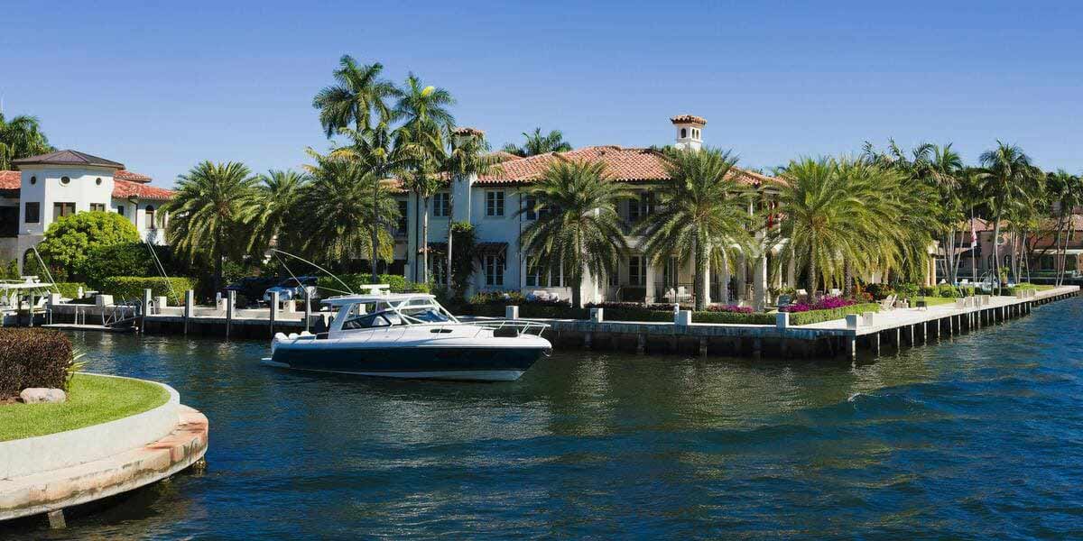 A boat sailing past upscale, waterfront homes down one of the many canals in Fort Lauderdale, Florida.