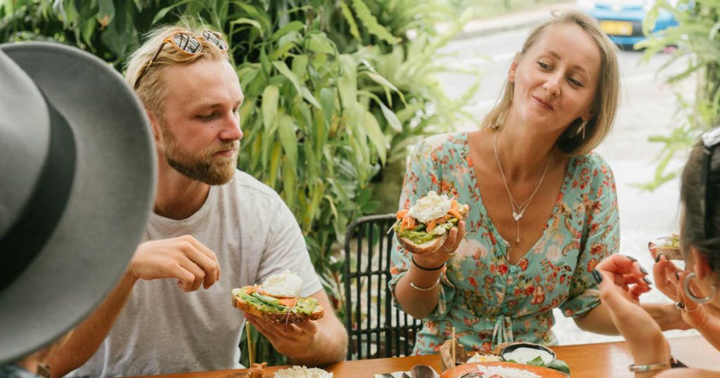 A happy couple enjoys an al fresco brunch, including avocado toast, with friends in Fort Lauderdale.