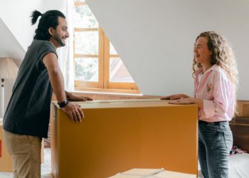 A man and woman are laughing together after packing their moving “first-day” box during a move.