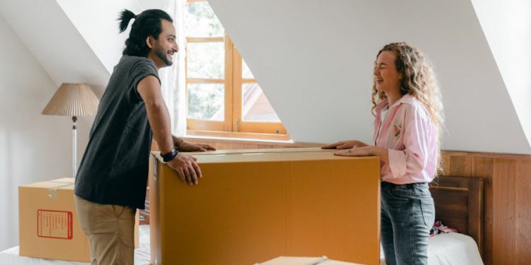 A man and woman are laughing together after packing their moving “first-day” box during a move.