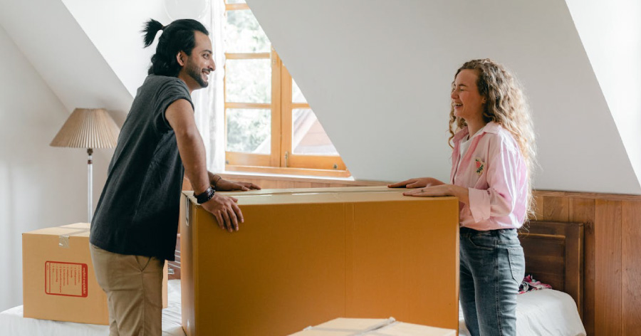 A man and woman are laughing together after packing their moving “first-day” box during a move.