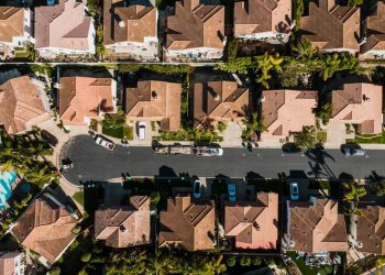 Aerial view of a suburban neighborhood featuring tree-lined streets, a cul-de-sac, and upscale single-family homes with clay-tiled roofs.