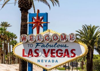 The iconic and colorful “WELCOME TO FABULOUS LAS VEGAS NEVADA” sign surrounded by palm trees on a sunny day.
