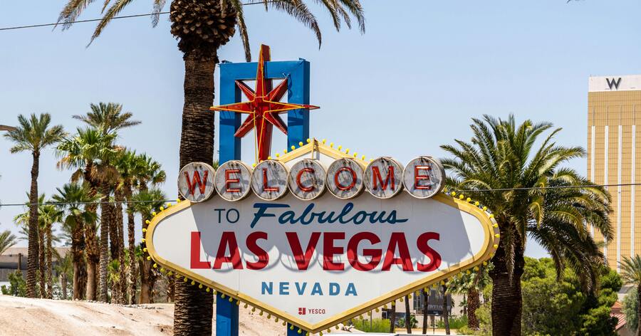 The iconic and colorful “WELCOME TO FABULOUS LAS VEGAS NEVADA” sign surrounded by palm trees on a sunny day.