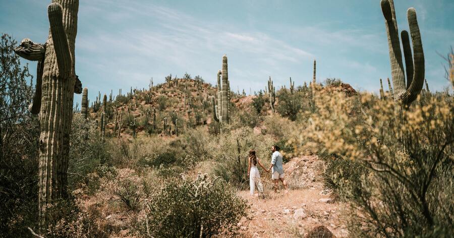 A couple is walking through a desert landscape on a sunny day, taking advantage of one of the perks of living in Las Vegas.
