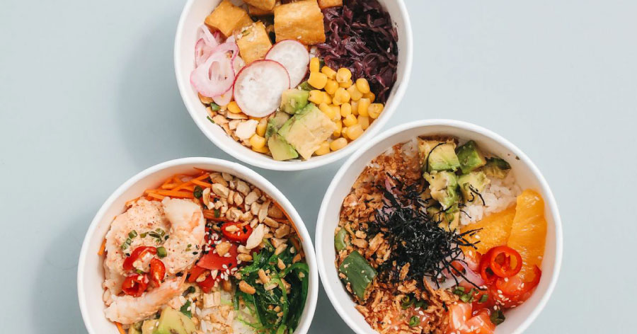 Overhead view of three white bowls filled with a colorful medley of Asian-fusion ingredients, like those served at one of the best restaurants in Denver.