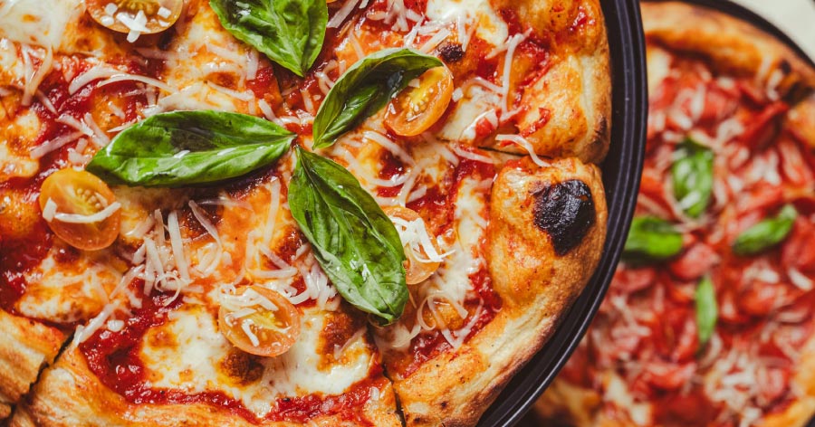 Close-up of a newly made pizza with fresh tomatoes and basil, like the ones served at Homegrown Tap & Dough, one of the most fun restaurants in Denver.