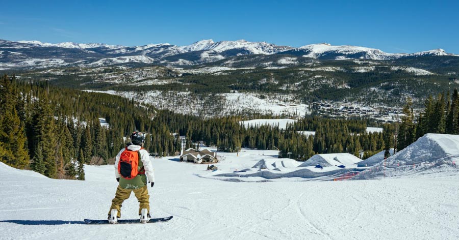 A snowboarder coasts down a snowy slope in Breckenridge on a sunny day, one of the many fun outdoor things to do in Denver and the surrounding area.