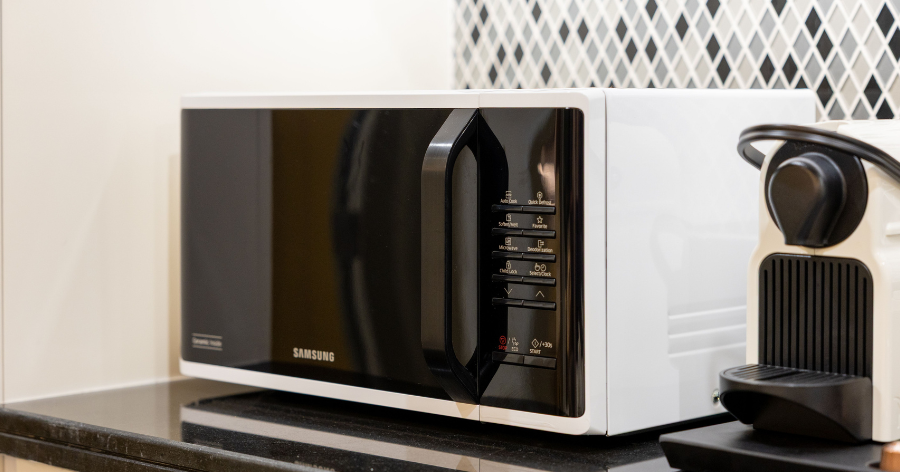 Microwave in a kitchen next to a coffee machine.