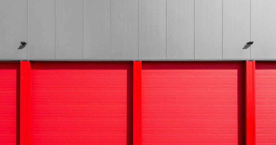 Exterior of a storage facility, like CubeSmart, with bright red roll-up storage unit doors.