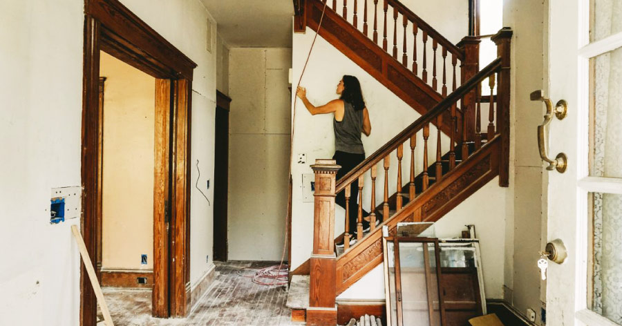 A woman is inspecting a wall in her house, which is mostly empty thanks to home renovation storage.