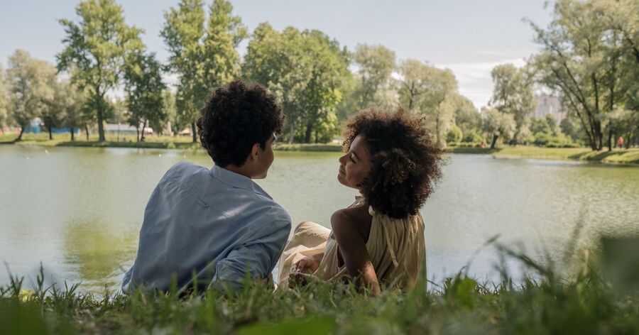 A young couple is relaxing by a lake in one of the best neighborhoods in Charlotte, enjoying the area's green spaces and peaceful surroundings.