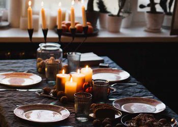 Table decorated for a dinner party with green tablecloth and candles.