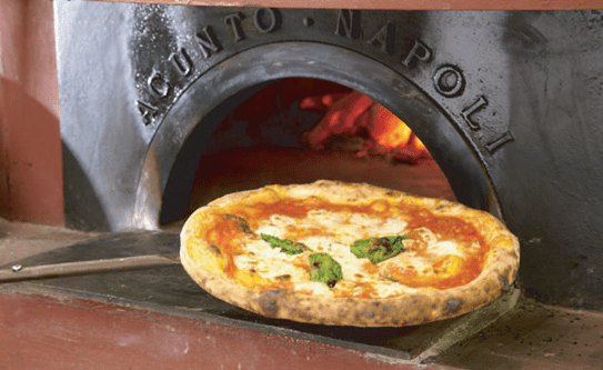 fresh pizza coming out of a brick oven