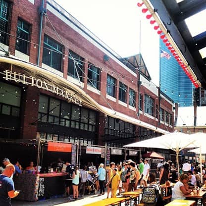 people shopping outdoors at the Fulton Stall Market in NYC