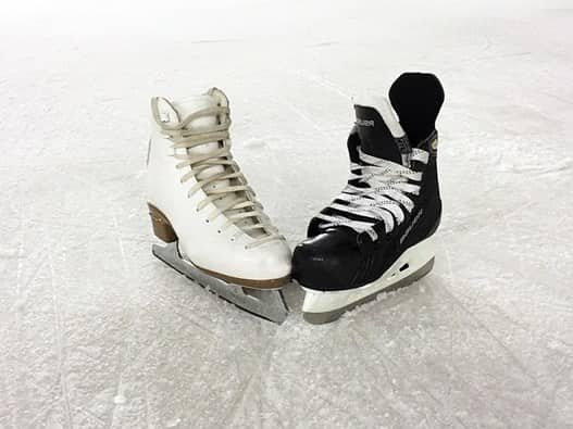 a black and a white ice skate on an ice rink