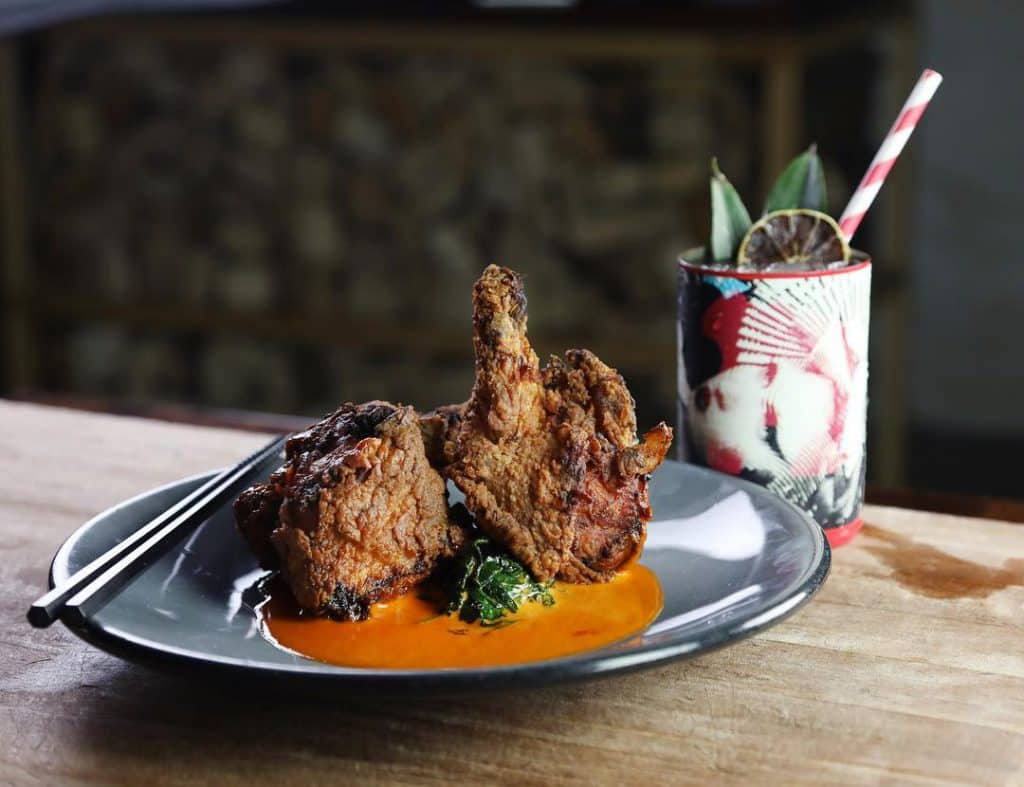 fried chicken next to a cocktail from Kyu in Miami, FL