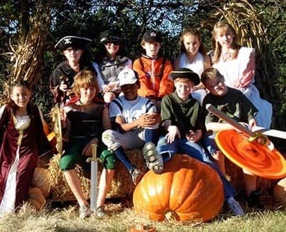 children sitting on pumpkins