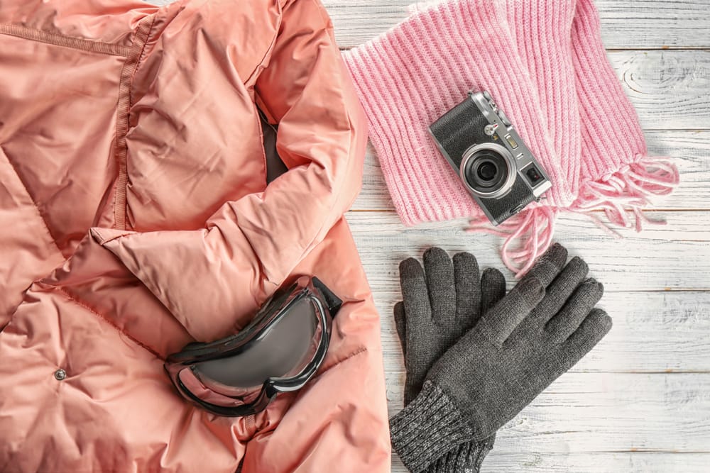 winter ski accessories, pink down jacket, scarf, camera, gloves and ski goggles