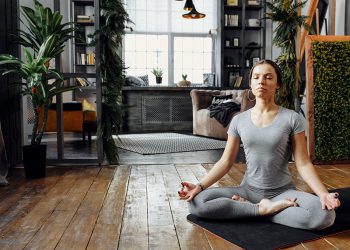 Woman meditating cross-legged in living room