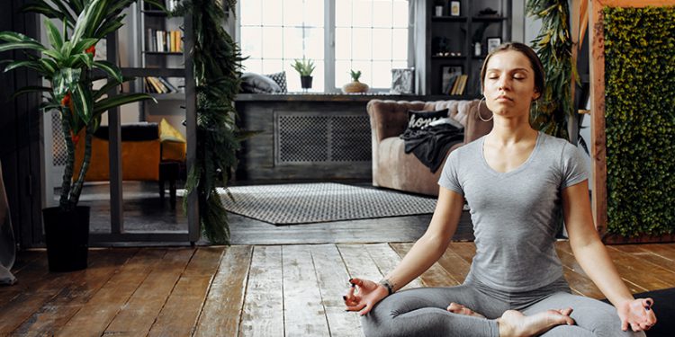 Woman meditating cross-legged in living room