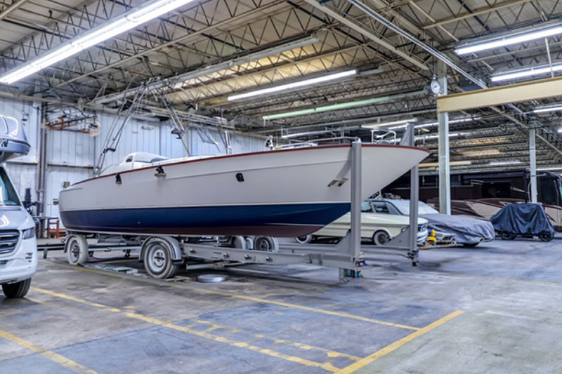 A parked boat on a trailer inside a large open storage garage.
