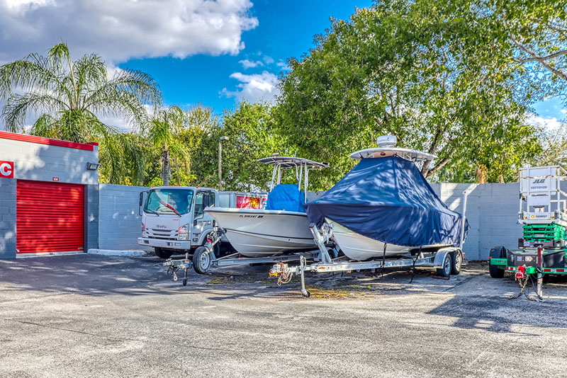 Boats are parked outside in front of a red storage door.
