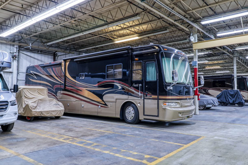 A large RV is parked in a climate-controlled storage garage.
